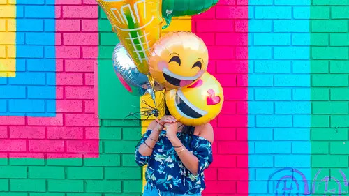Jeune devant mur coloré avec des ballons de bonhommes sourires